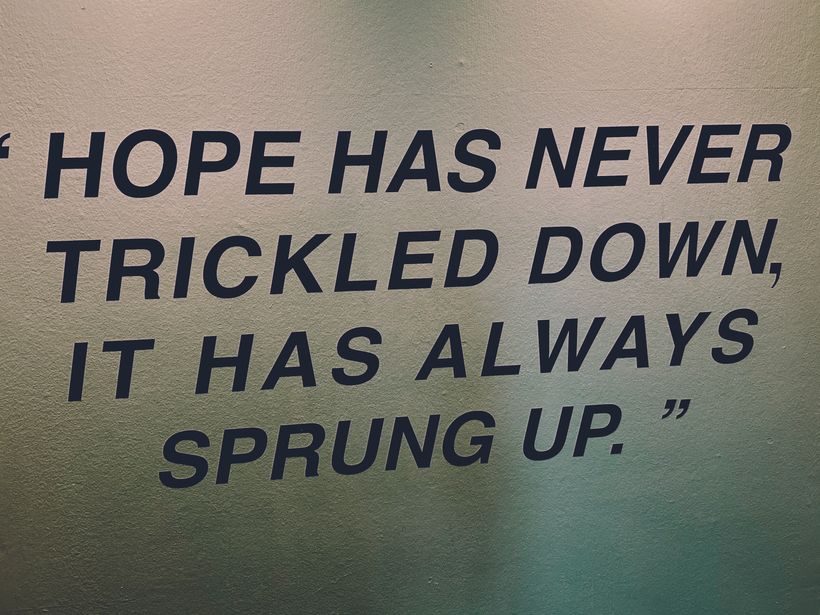 A quote, stencilled onto a wall in a stairwell: 'Hope has never trickled down, it has always sprung up'